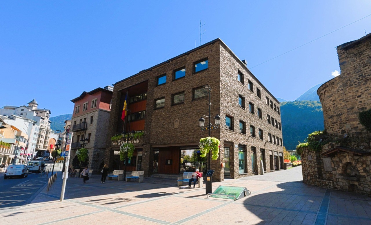 El limitado suelo urbanizable y la creciente demanda, impulsados por inversores locales y extranjeros, elevan el coste del metro cuadrado y dificultan el acceso a la vivienda asequible.
En los últimos cinco años, el mercado inmobiliario andorrano ha experimentado un ascenso vertiginoso que ha situado los precios de la vivienda al mismo nivel que en grandes ciudades españolas como Barcelona y, en menor medida, en Madrid.
Según datos de esta misma semana y el estudio del catedrático Luis Alberto Fabra, el precio del metro cuadrado en Andorra la Vella ha alcanzado los 5.607 euros, mientras que en Escaldes-Engordany se sitúa en torno a los 7.135,55 euros. En comparación, Barcelona marca los 5.449 euros/m² y Madrid 4.673 euros/m².
La escalada de precios, que acumula un incremento del 60% en el último lustro, se explica principalmente por tres factores: la escasez de suelo urbanizable, el crecimiento constante de la demanda –potenciado tanto por población local como por la llegada de inversores extranjeros– y la limitada oferta de nuevas viviendas.
Este contexto ha convertido la búsqueda de un piso asequible en una misión prácticamente imposible para muchas familias y trabajadores.
“El acceso a una vivienda digna se ha convertido en un desafío mayúsculo. La constante subida de los precios, impulsada por una demanda desbordada y una oferta muy limitada, nos lleva a cuestionar si estamos ante una burbuja especulativa o una evolución real del mercado”, explica el catedrático Luis Alberto Fabra, cuya investigación destaca que en octubre de 2024 se registró un máximo histórico de 5.400 euros/m².
El análisis del mercado se vuelve aún más revelador al calcular el precio de un piso de 80 metros cuadrados. En Les Escaldes-Engordany, dicho inmueble superaría el medio millón de euros; en Andorra la Vella, bastaría con añadir poco más de 50.000 euros al precio medio para alcanzar la cifra; mientras que en Barcelona el costo rondaría los 375.000 euros.
En contraste, ciudades medianas cercanas como Manresa o Tolosa ofrecen alternativas a precios considerablemente inferiores, con cifras aproximadas de 130.000 y 320.000 euros respectivamente, en tanto que en París, la capital francesa, un piso similar sobrepasa los 850.000 euros.